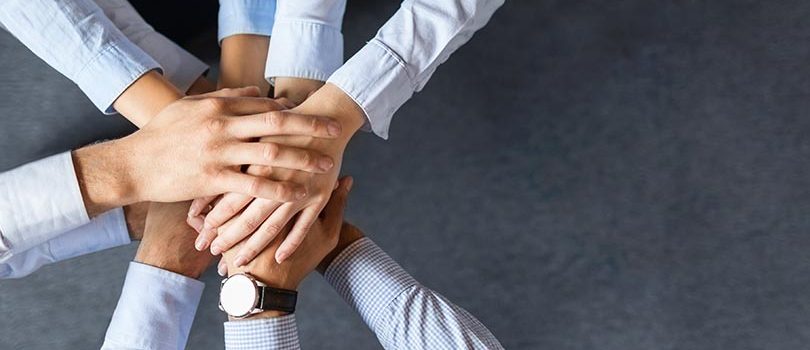 Close,Up,Top,View,Of,Young,Business,People,Putting,Their Close up top view of young business people putting their hands together. Stack of hands. Unity and teamwork concept.