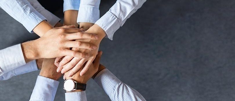 Close up top view of young business people putting their hands together. Stack of hands. Unity and teamwork concept.