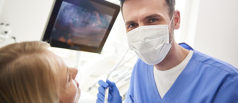 Portrait of confident dentist using dental drill and dental mirror Portrait of confident dentist using dental drill and dental mirror