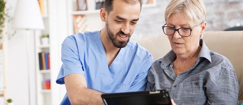 Health visitor helping senior woman to use tablet Health visitor helping senior woman to use tablet in nursing home.