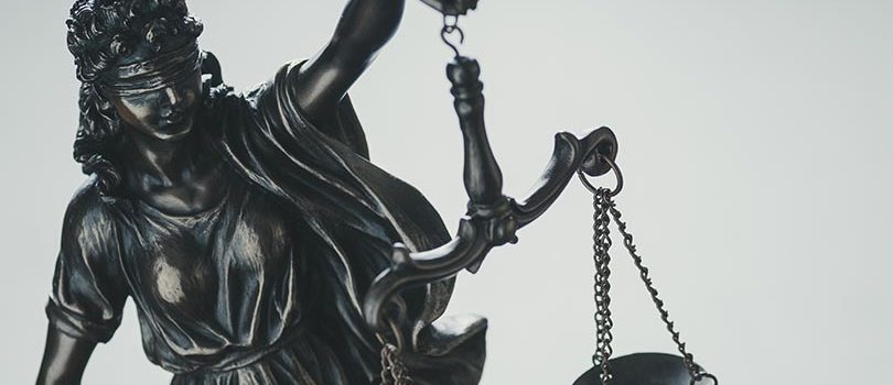 Statue of Justice holding aloft scales Statue of Justice holding aloft scales in her hand symbolic of law enforcement over a light grey background
