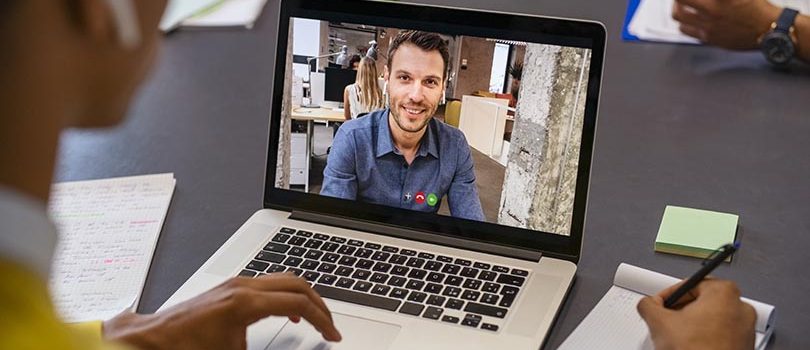 Business man on video call Smiling business partners talking through video call. Back view of african businessman in office doing video chat calling a client. Young man and his business colleague talking to each other through a video conference on digital tablet screen.