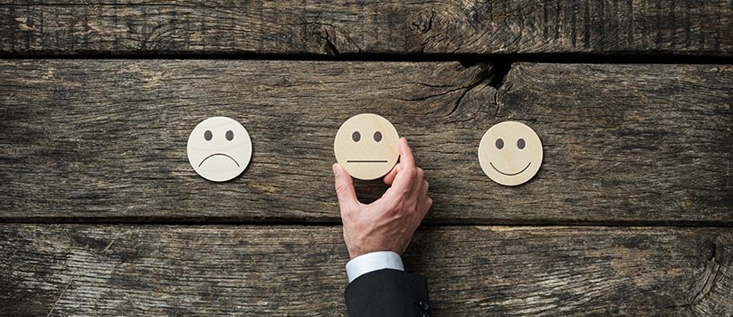 Customer service review and feedback conceptual image Customer service review and feedback conceptual image - male hand choosing an average face icon among three options.