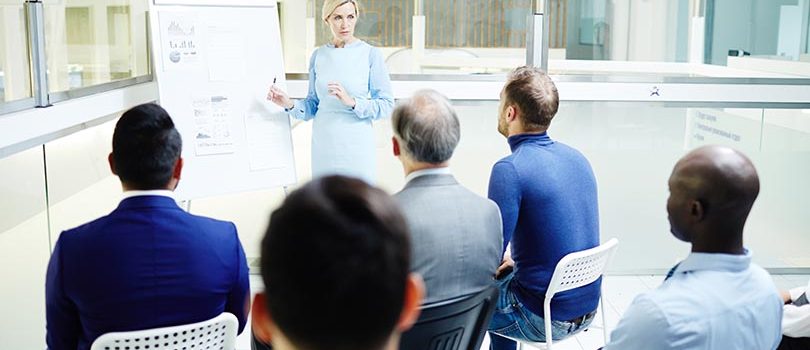 Formació Confident mature speaker making report for audience by whiteboard at seminar or conference