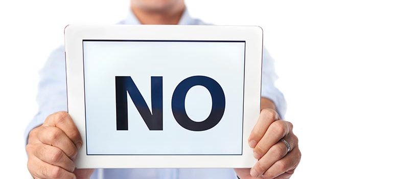 Negative Smiling man holding tablet computer with big no