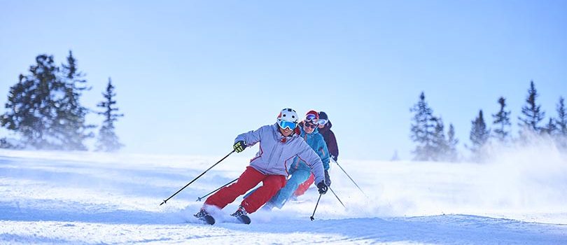 Row of male and female skiers skiing down snow covered ski slope, Aspen, Colorado, USA