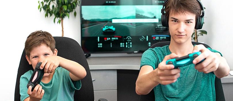 Teenager boy online plays a  computer game with headphones and a joystick, game console.