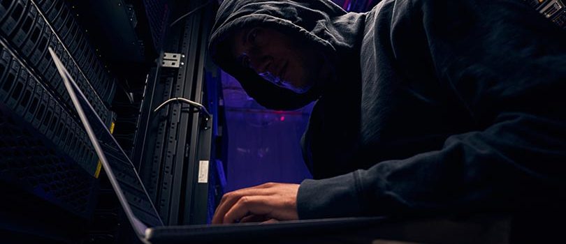 Low angle of hacker carrying out cyberattack on data center computer system in server room