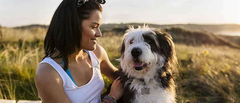 Smiling woman with dog on boardwalk in dunes