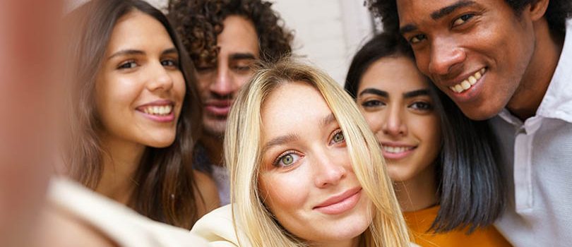 Multi-ethnic group of friends taking a selfie together while having fun outdoors. Multi-ethnic group of friends taking a selfie together while having fun in the street. Blonde Russian woman in the foreground.