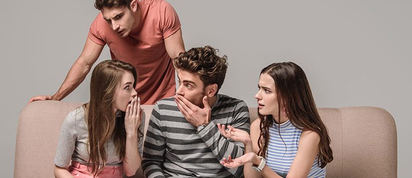 happy young friends gossiping and sitting on sofa on grey happy young friends gossiping and sitting on sofa on grey